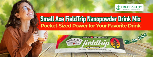 Smiling woman drinking from a mug outdoors next to a product banner for Small Axe FieldTrip Nanopowder Drink Mix